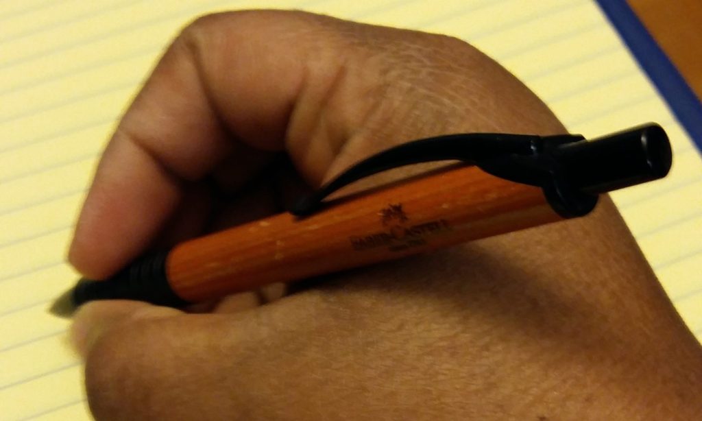 Black writer writing with brown ballpoint pen.