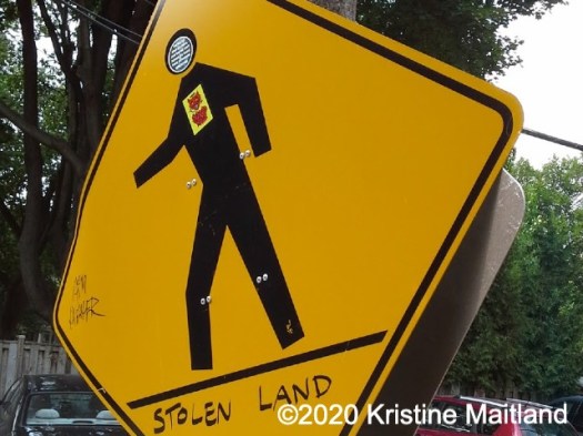 Stolen land written on a yellow Caution sign on a roadside.